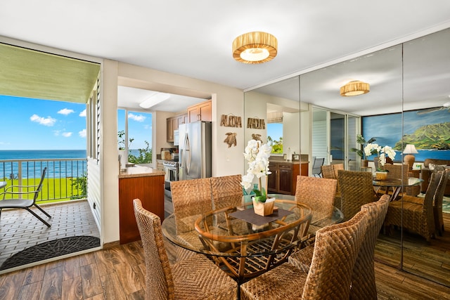 dining space featuring a water view, a wall of windows, and dark wood-type flooring