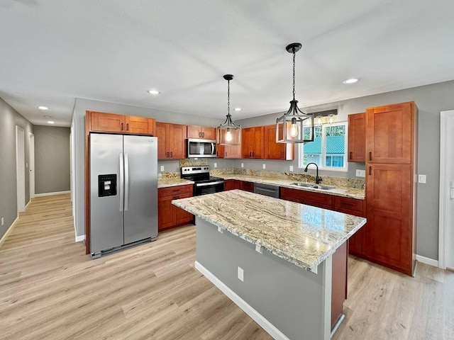 kitchen with sink, appliances with stainless steel finishes, hanging light fixtures, light stone countertops, and a kitchen island