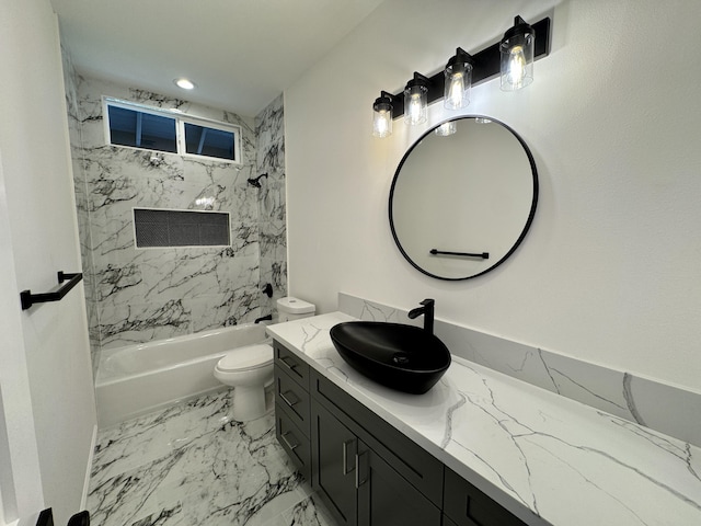 full bathroom featuring tiled shower / bath, vanity, and toilet