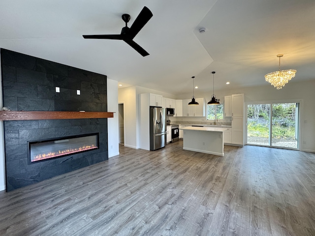 kitchen featuring a kitchen island, pendant lighting, a fireplace, white cabinetry, and stainless steel appliances