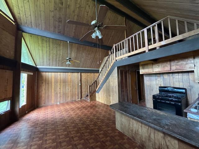 interior space with beam ceiling, parquet floors, high vaulted ceiling, and wood walls