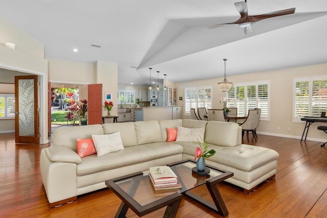 living room featuring wood-type flooring, vaulted ceiling, sink, and a healthy amount of sunlight