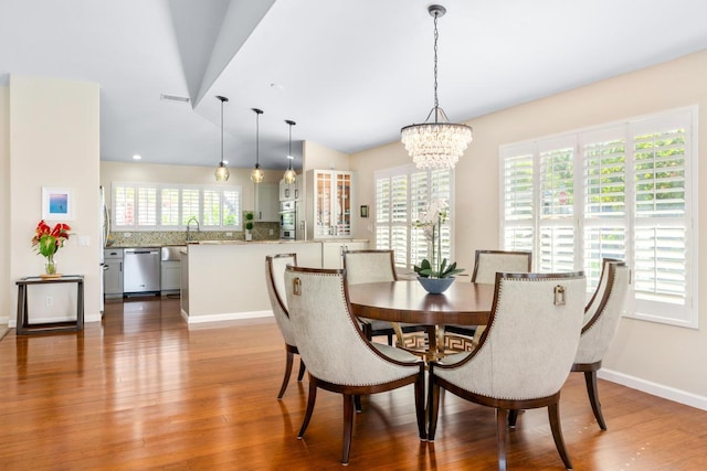 dining area featuring hardwood / wood-style flooring, a healthy amount of sunlight, and a notable chandelier