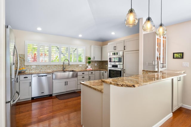 kitchen featuring decorative light fixtures, appliances with stainless steel finishes, sink, and kitchen peninsula