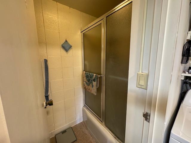 bathroom featuring washer / dryer and combined bath / shower with glass door