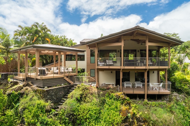 back of property with a wooden deck, outdoor lounge area, and ceiling fan