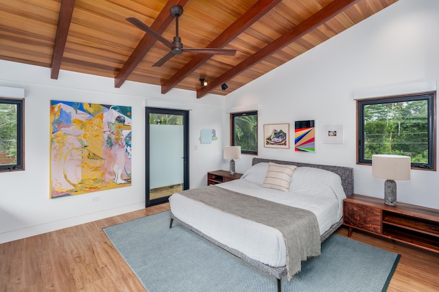 bedroom with multiple windows, hardwood / wood-style floors, and beam ceiling