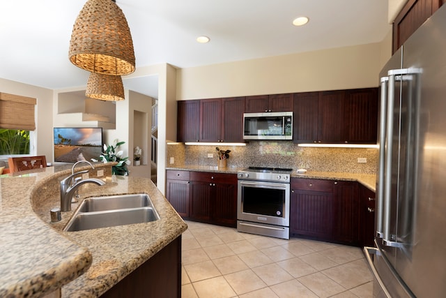 kitchen with sink, appliances with stainless steel finishes, hanging light fixtures, tasteful backsplash, and light stone countertops