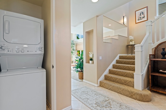 clothes washing area featuring stacked washer and clothes dryer and light tile patterned floors