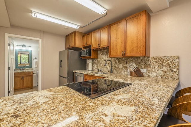 kitchen with appliances with stainless steel finishes, tasteful backsplash, sink, a breakfast bar area, and kitchen peninsula