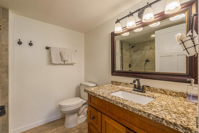 bathroom with a tile shower, vanity, tile patterned flooring, and toilet