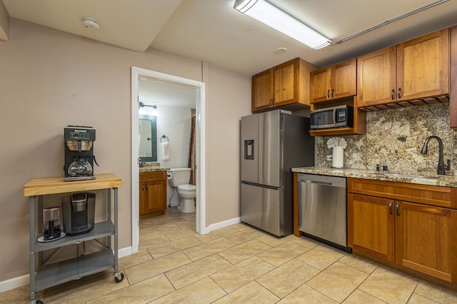 kitchen featuring appliances with stainless steel finishes, sink, backsplash, light tile patterned floors, and light stone counters