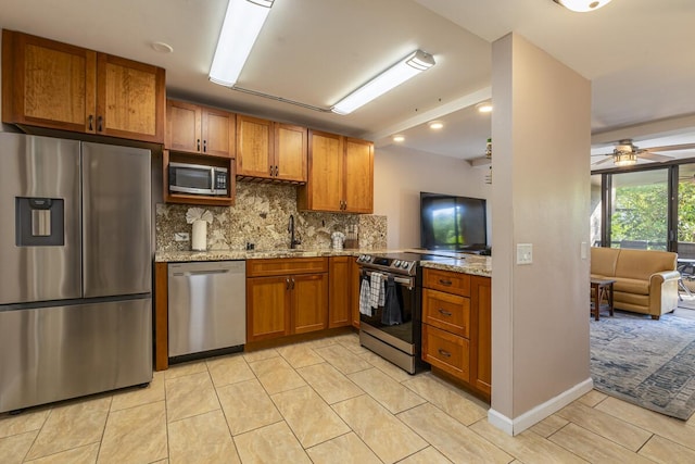 kitchen with tasteful backsplash, sink, ceiling fan, stainless steel appliances, and light stone countertops