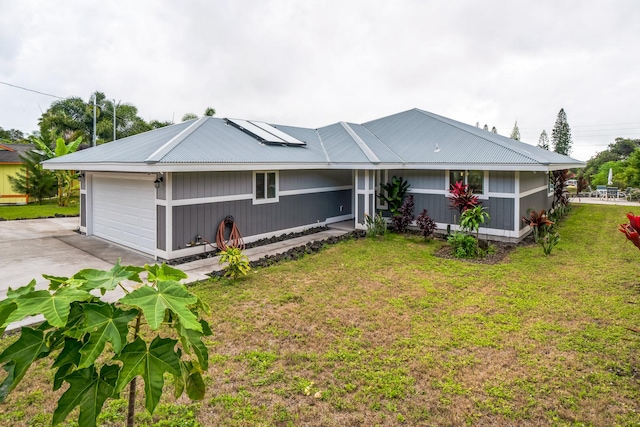 ranch-style house with roof mounted solar panels, a front lawn, metal roof, and concrete driveway