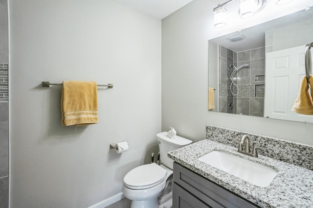 bathroom with tiled shower, vanity, toilet, and baseboards