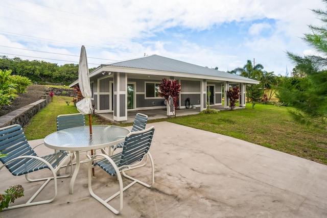 back of house with outdoor dining area, a patio area, a lawn, and metal roof