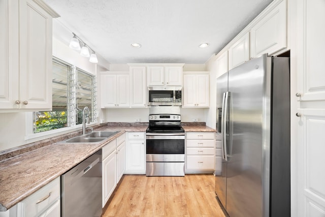 kitchen with white cabinetry, stainless steel appliances, sink, and light wood-type flooring