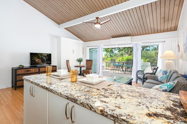 interior space featuring white cabinetry, plenty of natural light, light stone countertops, and an AC wall unit