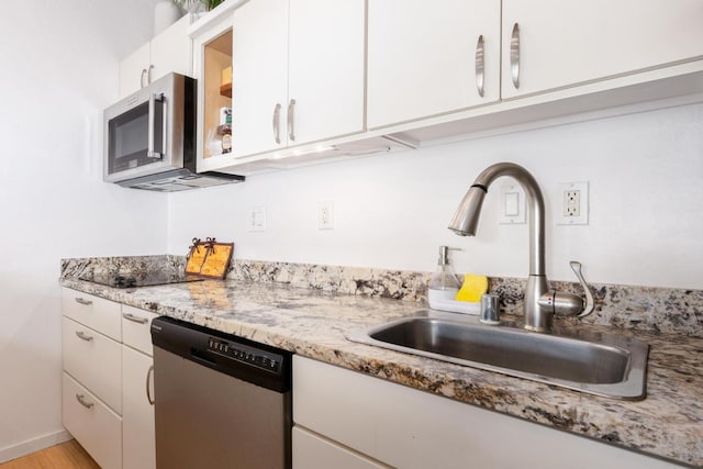 kitchen featuring sink, appliances with stainless steel finishes, light stone countertops, white cabinets, and light wood-type flooring