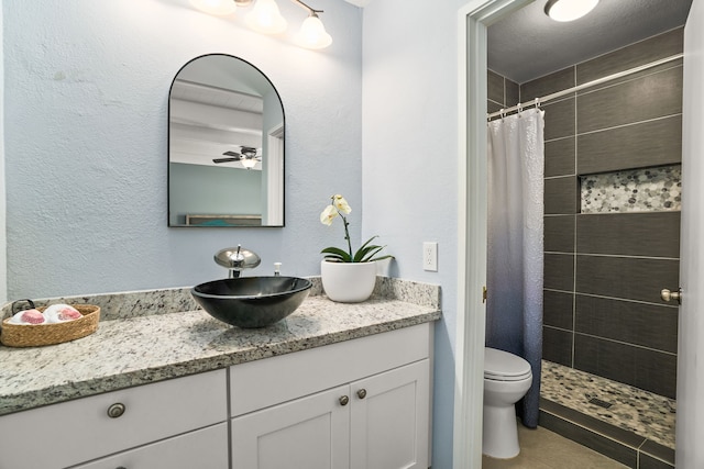 full bath with tile patterned flooring, toilet, tiled shower, and vanity