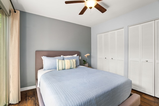 bedroom featuring baseboards, two closets, wood finished floors, and a ceiling fan