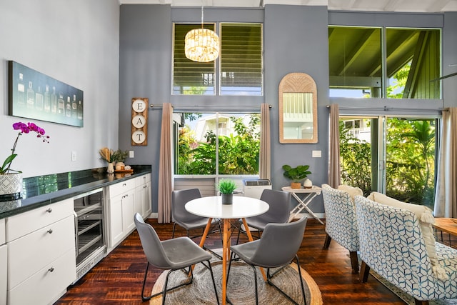 interior space with a wealth of natural light, dark wood-style floors, a notable chandelier, and beverage cooler