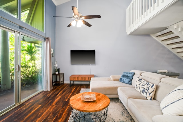 living area featuring baseboards, stairs, wood finished floors, high vaulted ceiling, and a ceiling fan