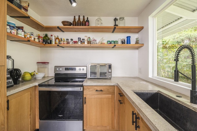 kitchen with sink, stainless steel range with electric cooktop, and a textured ceiling