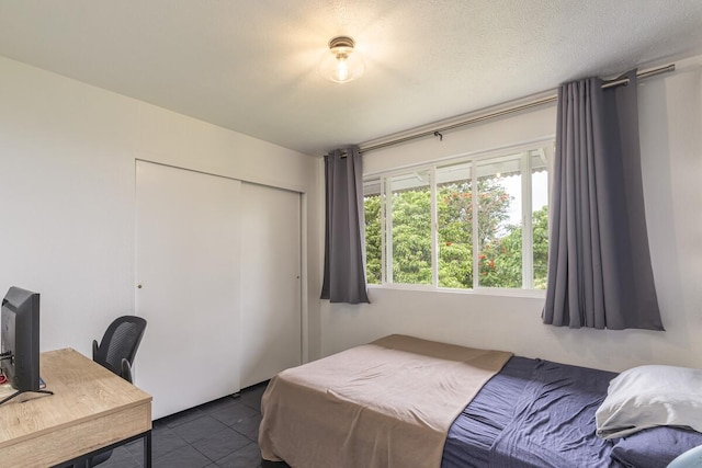 bedroom with a textured ceiling, a closet, and dark tile patterned floors