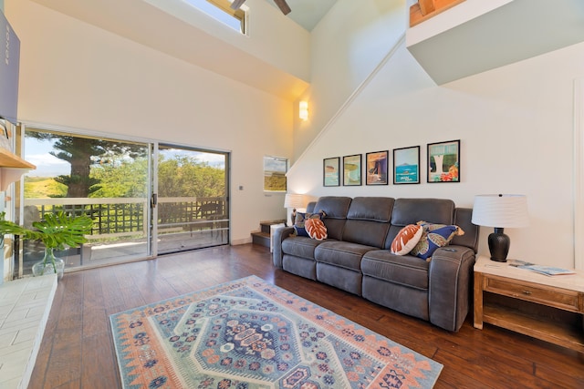 living room with a high ceiling, a healthy amount of sunlight, and dark wood-type flooring