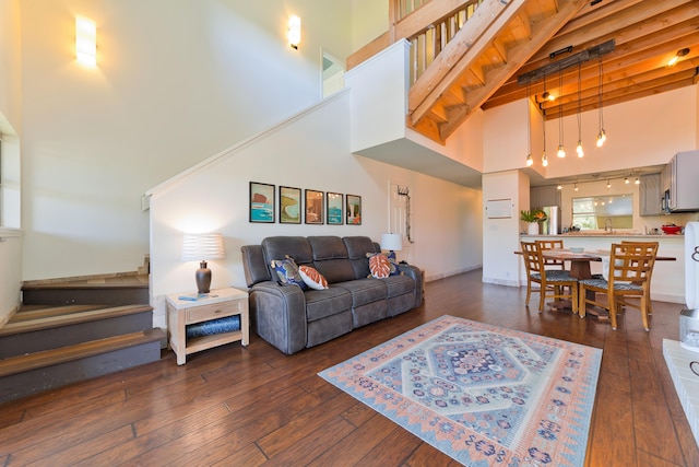 living room featuring dark hardwood / wood-style flooring, a towering ceiling, and beamed ceiling