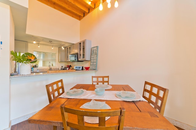 dining space featuring beamed ceiling, rail lighting, and sink