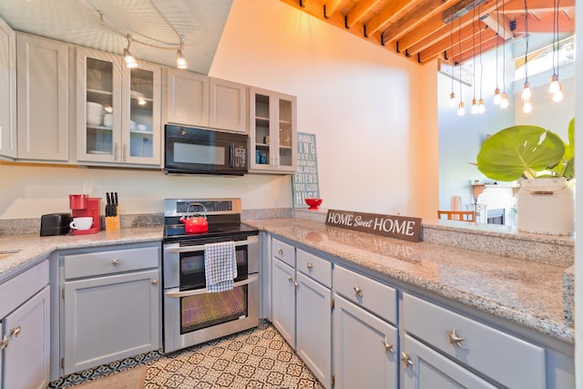 kitchen featuring light stone counters, double oven range, decorative light fixtures, and gray cabinets