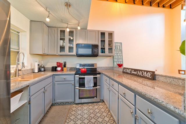 kitchen with sink, light stone counters, decorative light fixtures, double oven range, and gray cabinets