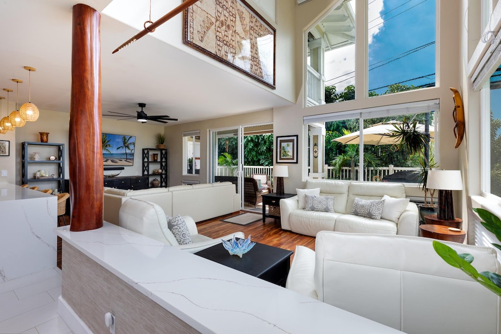 living room with light hardwood / wood-style floors, a towering ceiling, and ceiling fan