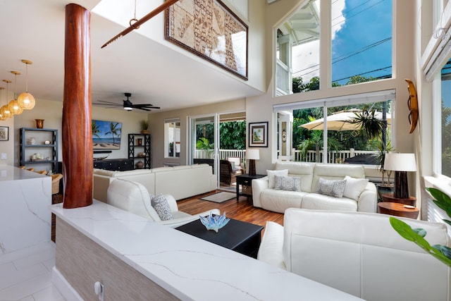 living room featuring a ceiling fan, light wood-style floors, and a high ceiling