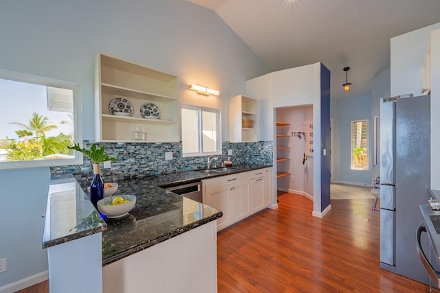 kitchen with appliances with stainless steel finishes, sink, white cabinets, backsplash, and dark stone counters