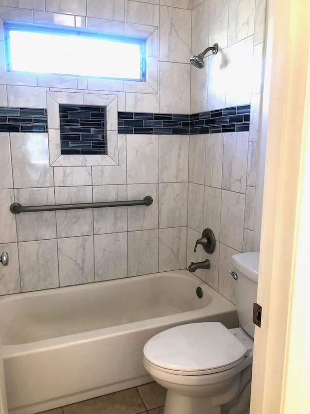 bathroom with tiled shower / bath combo, tile patterned flooring, and toilet