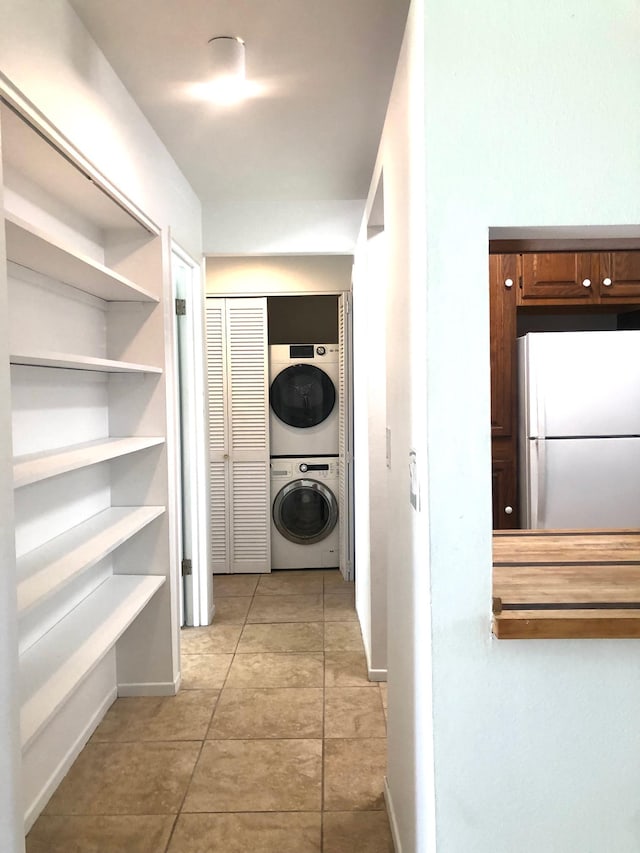 laundry room featuring light tile patterned floors and stacked washer / dryer