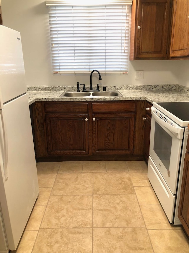 kitchen featuring light stone countertops, sink, light tile patterned floors, and white appliances