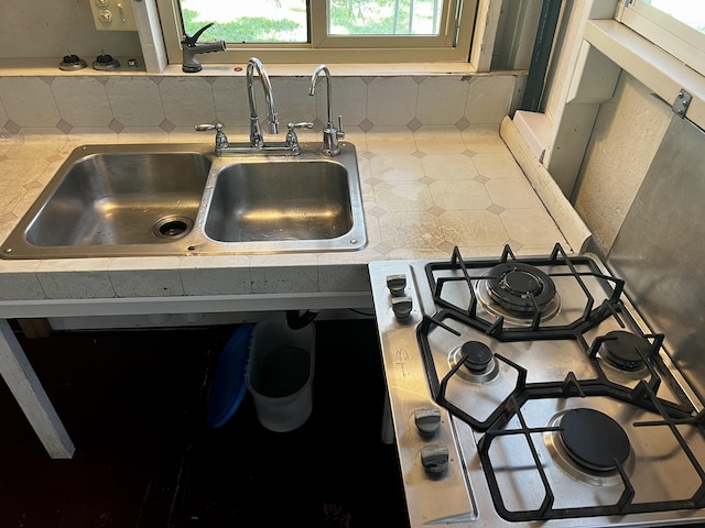 interior details featuring stovetop, sink, and backsplash