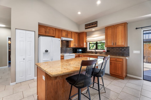 kitchen featuring lofted ceiling, sink, a center island, light tile patterned floors, and white appliances