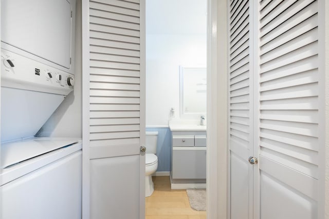 bathroom with stacked washer / dryer, toilet, wood-type flooring, and vanity