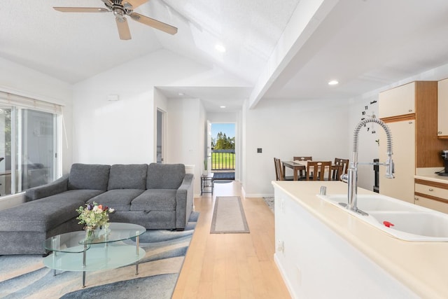 interior space featuring vaulted ceiling, ceiling fan, sink, and light hardwood / wood-style flooring