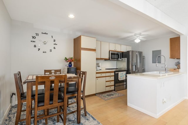 kitchen featuring sink, appliances with stainless steel finishes, kitchen peninsula, cream cabinetry, and light wood-type flooring