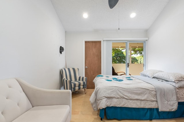 bedroom featuring access to exterior, light hardwood / wood-style floors, and a textured ceiling