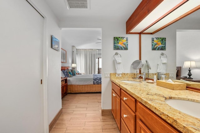 full bathroom with connected bathroom, wood finish floors, a sink, visible vents, and double vanity