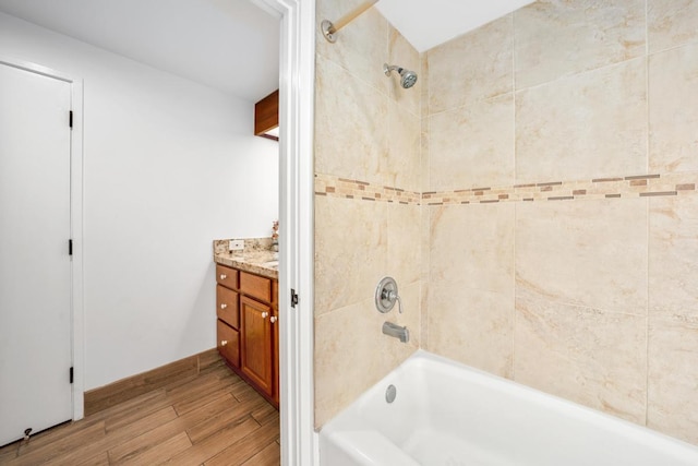 bathroom featuring shower / washtub combination, wood finished floors, vanity, and baseboards