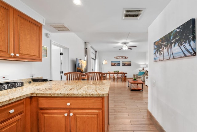 kitchen with a peninsula, light stone countertops, wood tiled floor, and visible vents