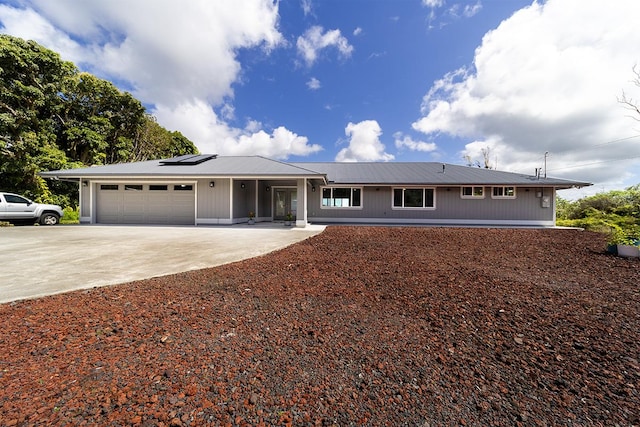 single story home with a garage, concrete driveway, and solar panels